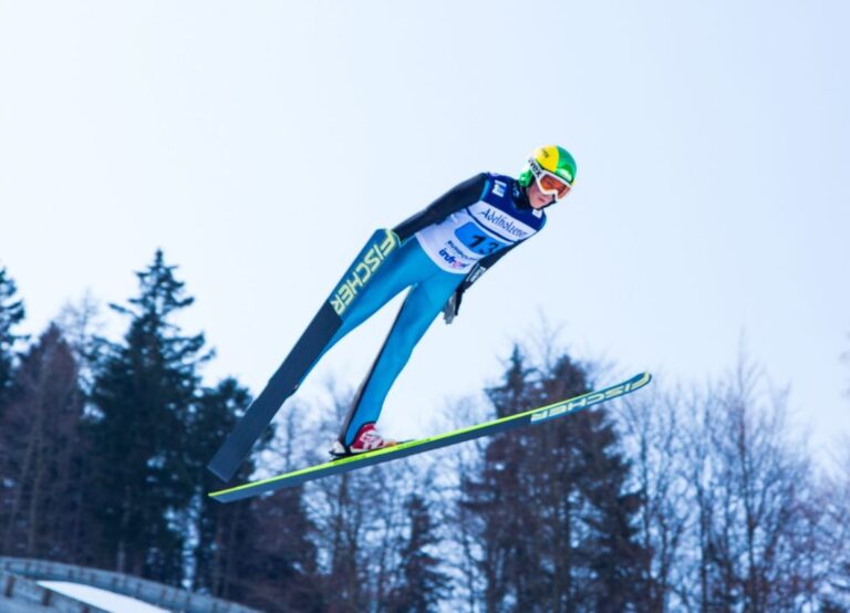 Skispringer im Flug bei einem Wettkampf der Nordischen Kombination.