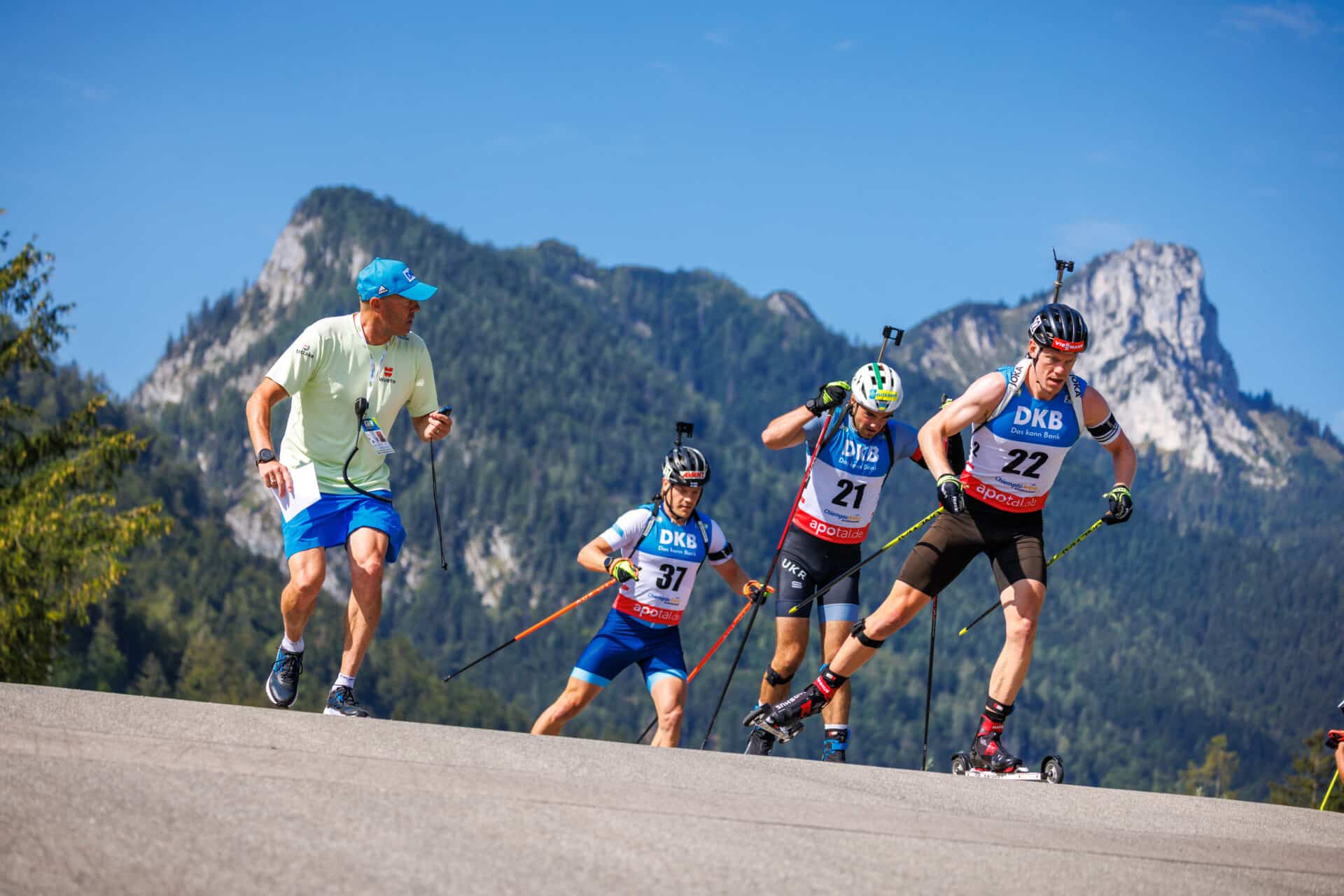 Biathleten beim Rollski-Wettkampf mit Trainerbegleitung vor Alpenkulisse in Ruhpolding